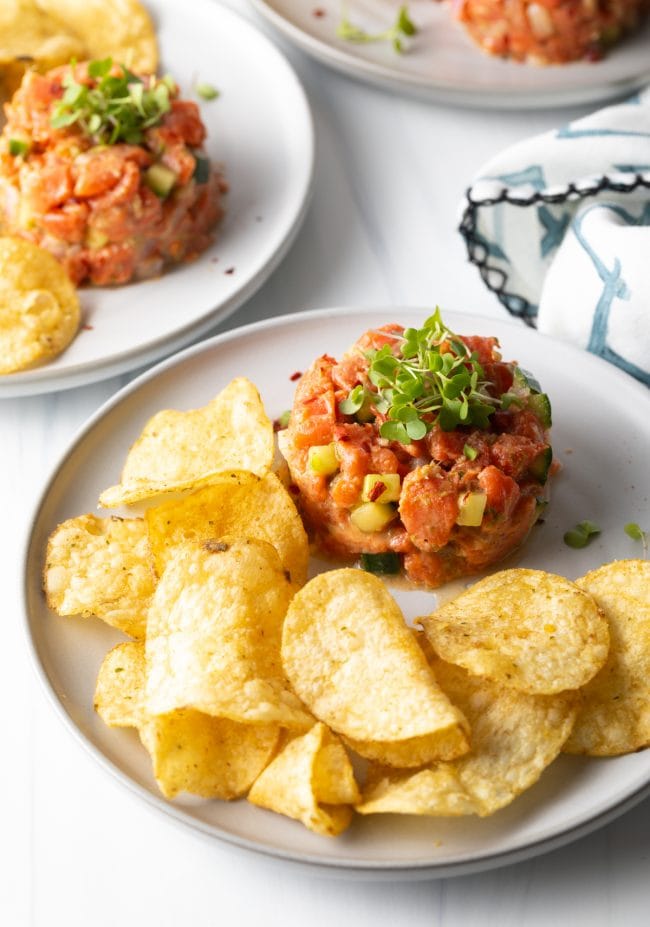 salmon tartare with microgreens on a plate with chips