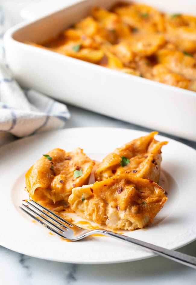 Serving of cheesy seafood pasta on a white plate with fork.