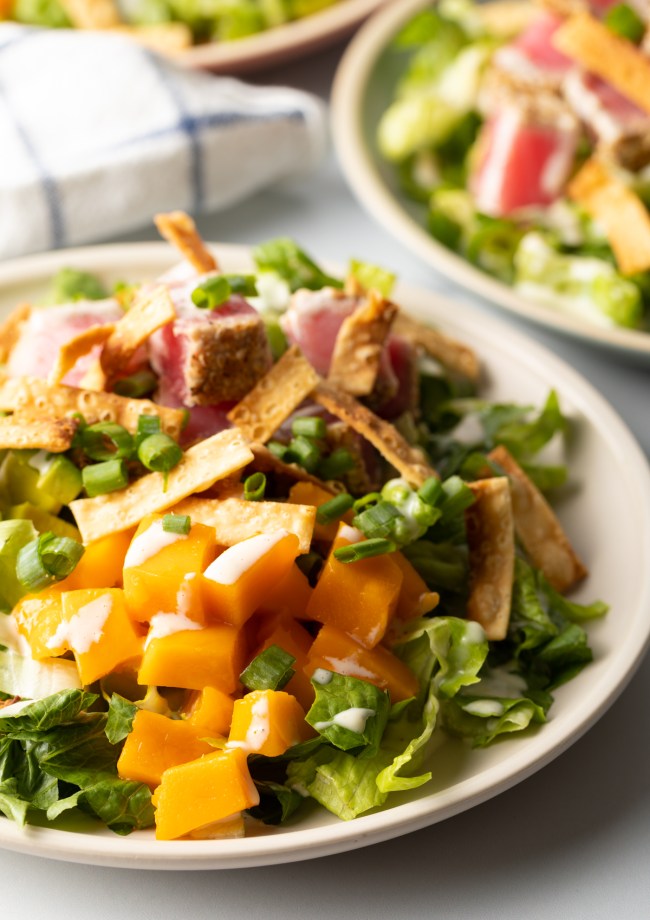 salad on a plate with mango and scallions, crispy onions and cubed seared tuna