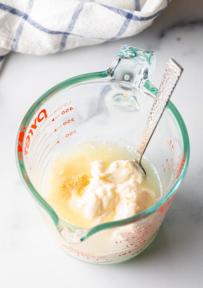 ingredients to make lime aioli in a glass measuring cup with spoon