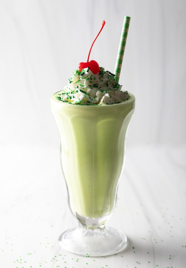 Final image of peppermint shamrock shake recipe in a glass, with cherry on top.