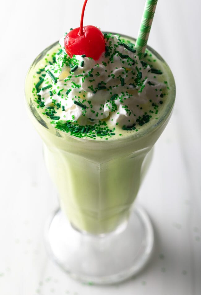 Peppermint shamrock shake in a glass, with cherry on top.