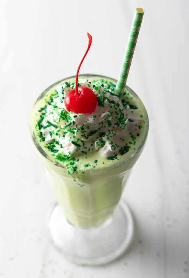 Peppermint shamrock shake in a glass, with cherry on top.