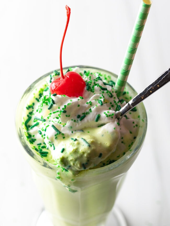 Metal spoon with spoonful of peppermint shake held towards camera.