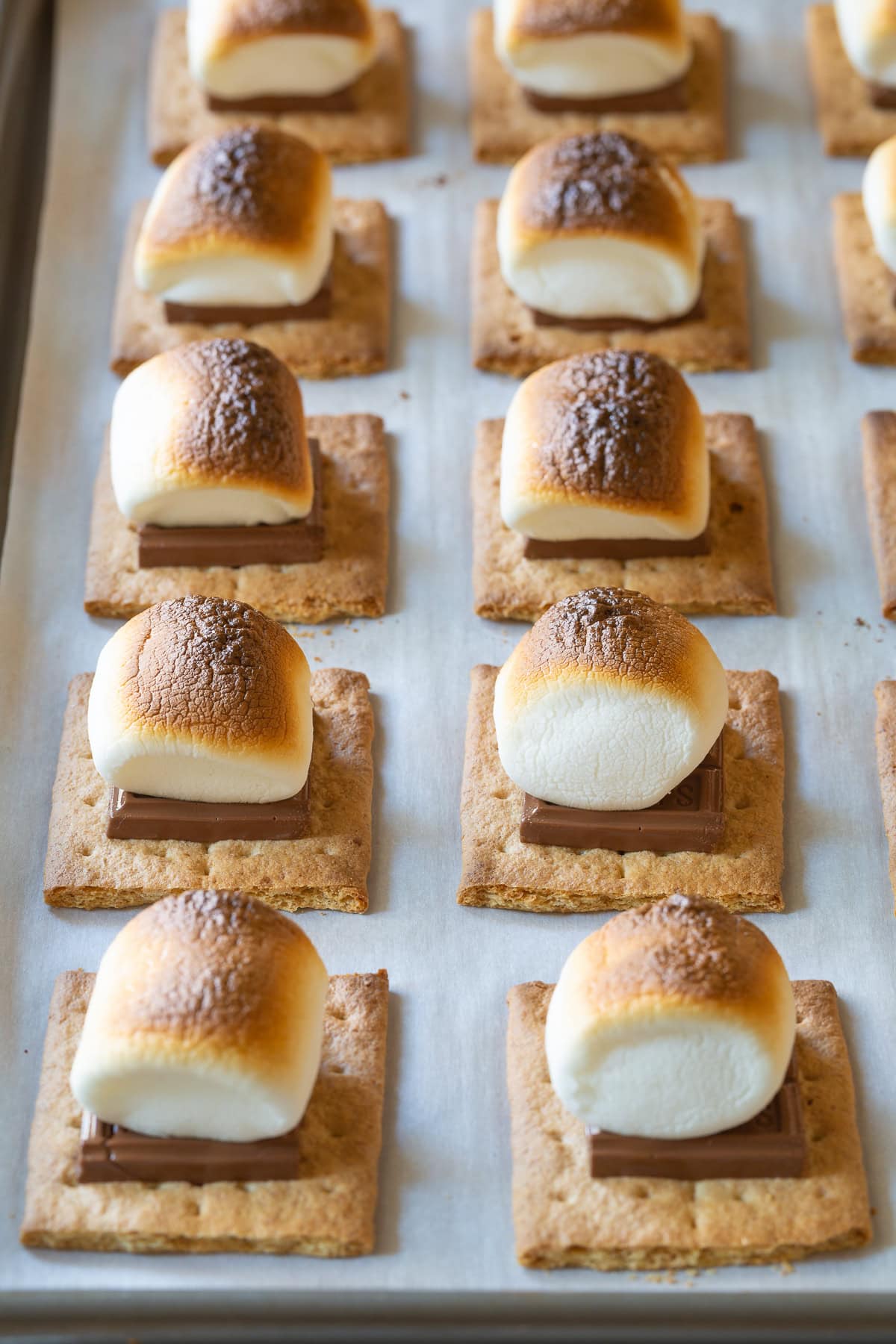 Broiled s'mores lined up on a baking sheet. 