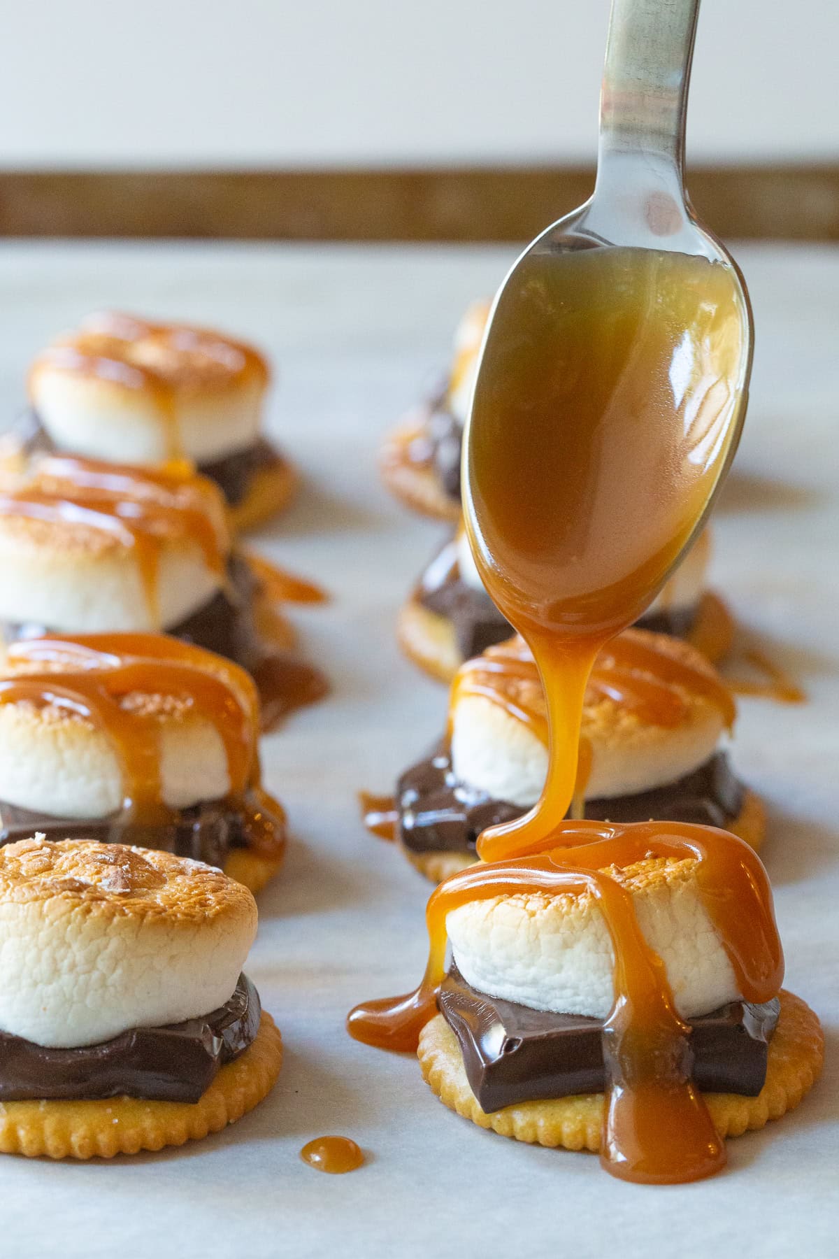 Spooning salted caramel sauce on top of ritz crackers smores. 