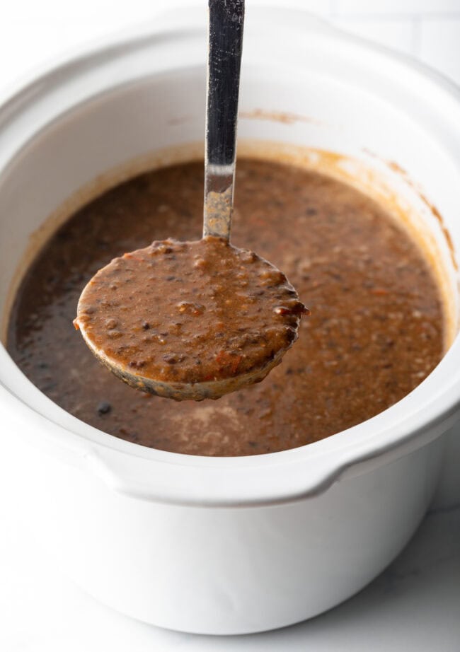 easy crockpot black bean soup - ladle lifting soup up