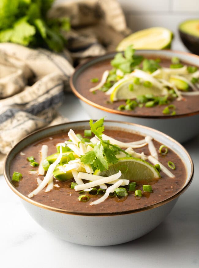 slow cooker black bean soup in a gray bowl with fresh garnishes