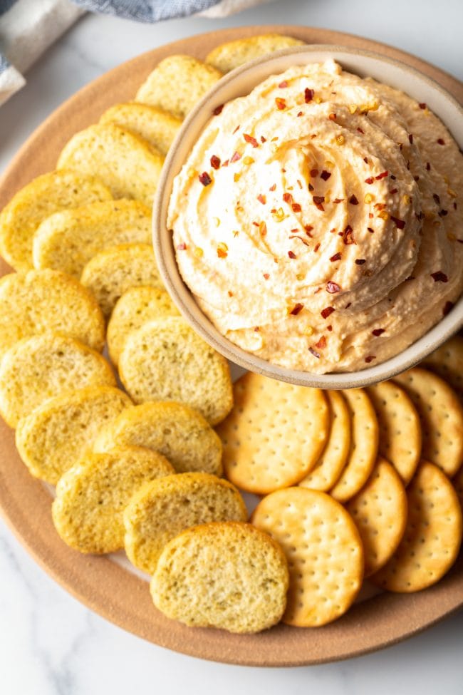 Smoked Cheese Spread - top view bowl of cheese spread with crushed red pepper on top, surrounded by slices of crunchy bread and crackers