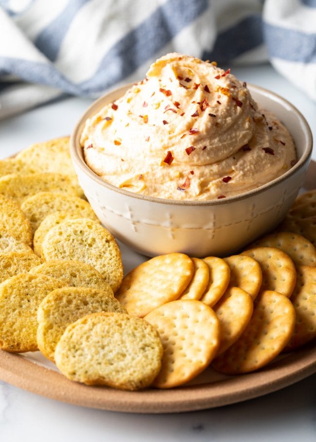 Smoked Cheese Spread - bowl of smoked cheese and sour cream dip on a plate surrounded by crackers and toasted bread slices