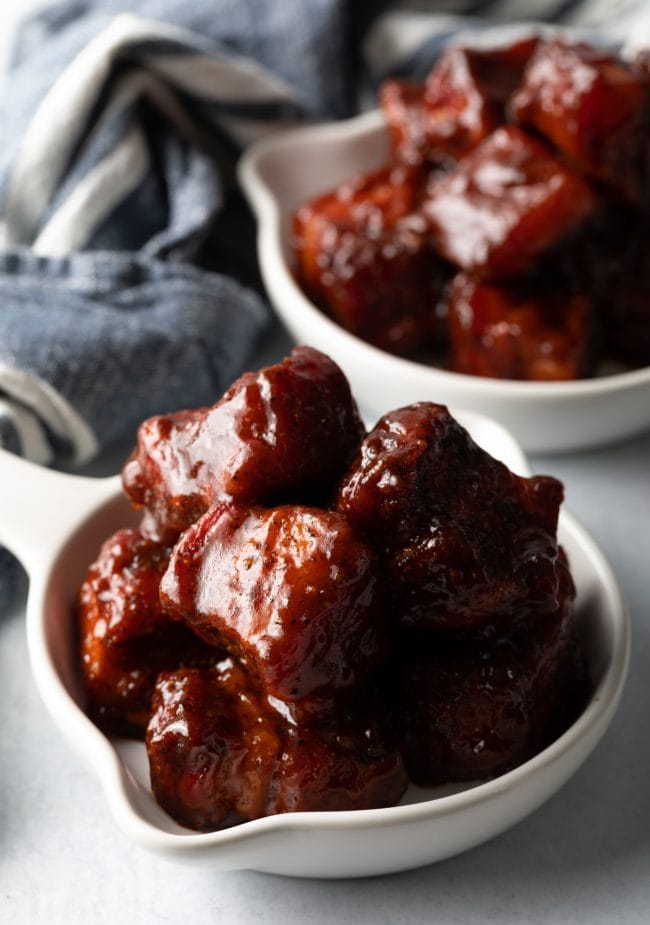 White bowls of pork belly burnt ends with bbq sauce.