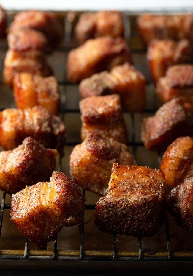 Close view smoked pork belly pieces on a wire rack.