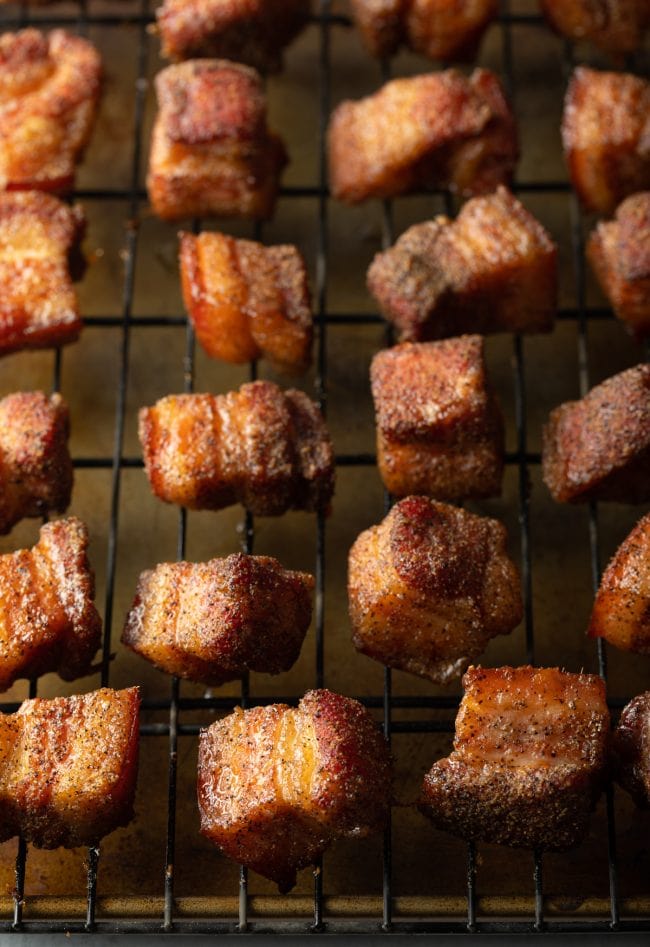 Cubes of smoked pork burnt ends on a wire rack.