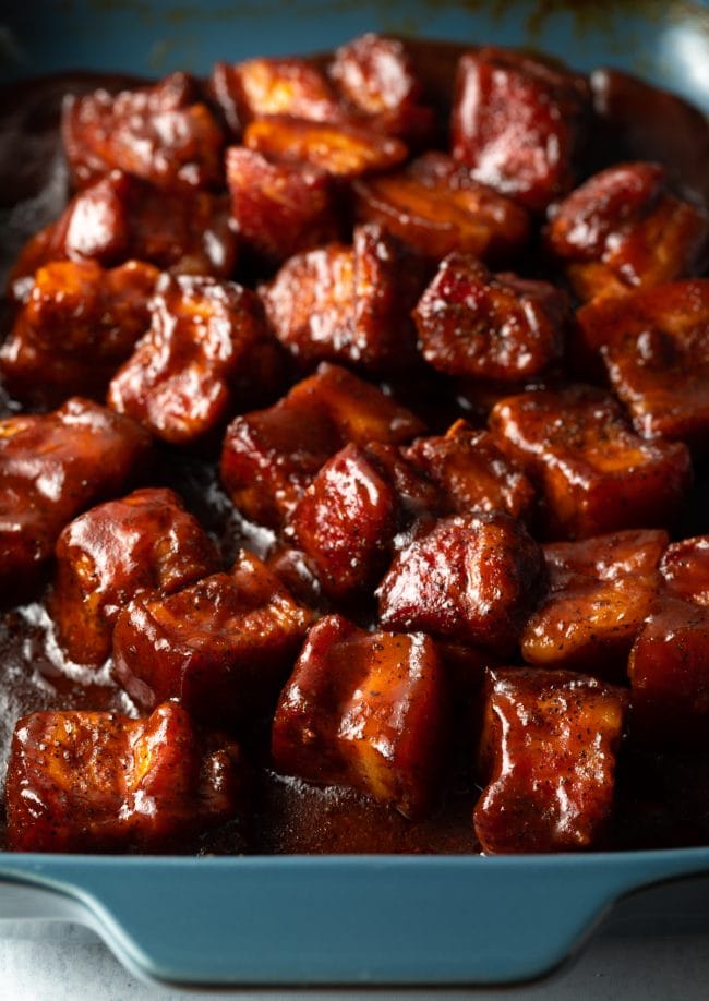 Dish with cubes of smoked pork burnt ends recipe tossed in barbecue sauce.