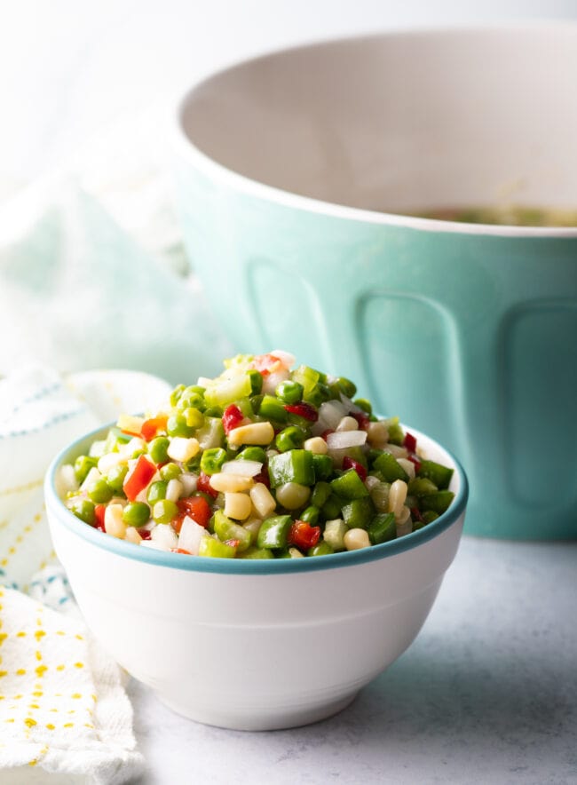 Marinated Vegetable Salad - Finished shoepeg corn, pea, and marinated veggies salad in a white bowl.