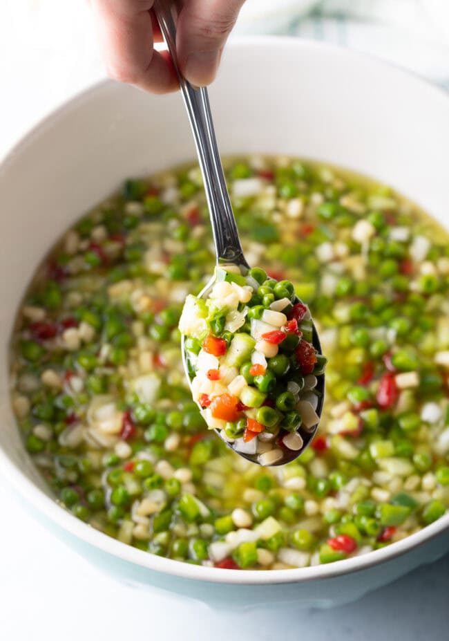 Metal spoon showing scoop of veggie salad to camera.