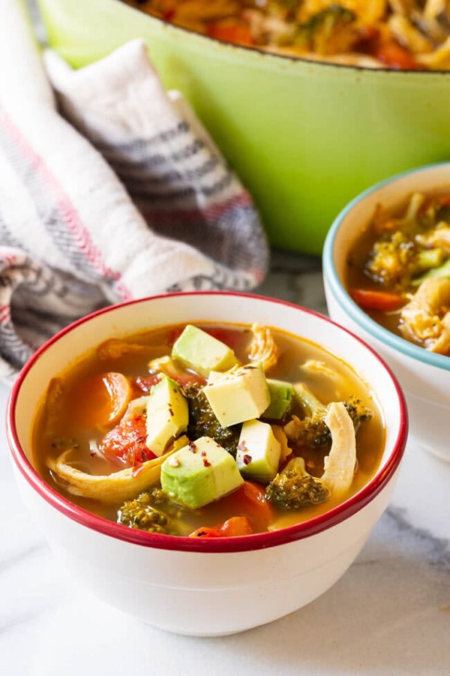 Two bowls of detox soup topped with diced avocado. 