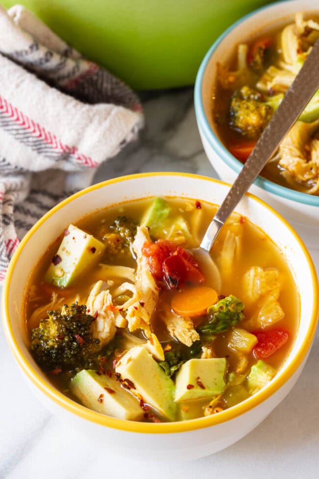 Bowl of chicken vegetable soup with a silver spoon. 