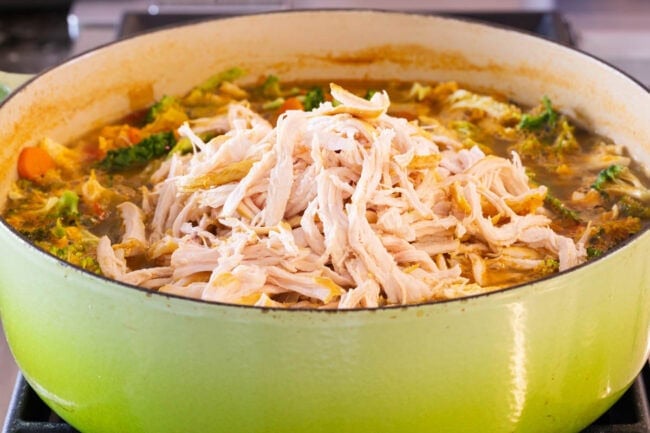 Southwest chicken soup with shredded chicken being added back into the soup. 