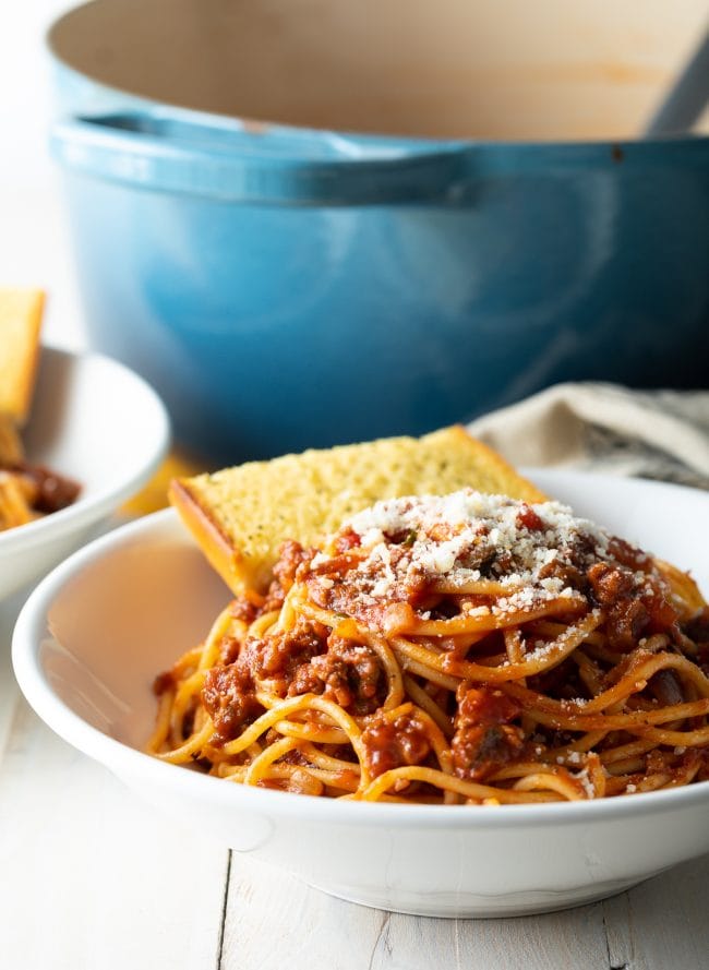 spaghetti sauce recipe with meat in bowl with garlic bread.