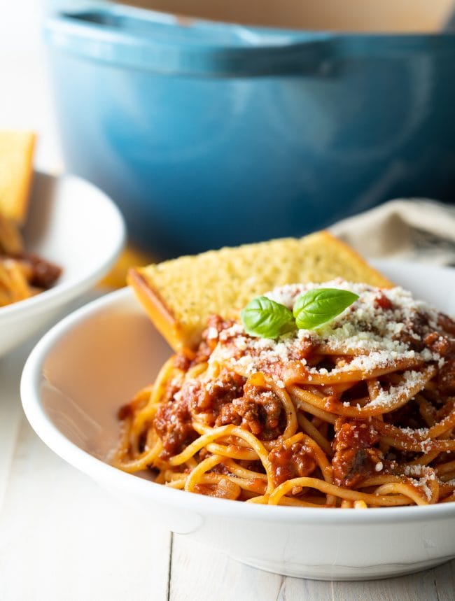 Spaghetti with meat sauce in a bowl served with garlic bread. 