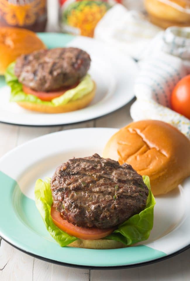 Burger being assembled on a plate. 