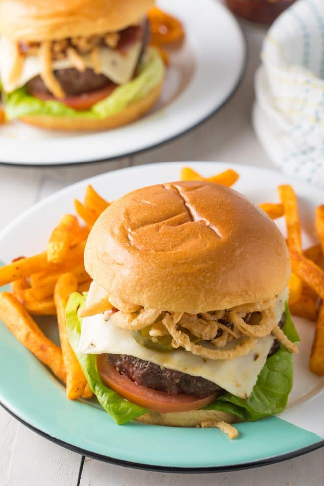 Spicy Burger on a white plate with fries on the side. 