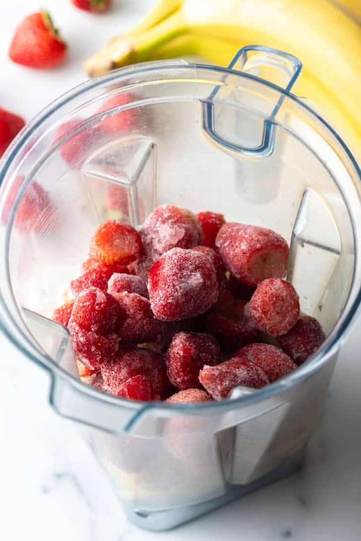 Frozen strawberries in a blender jar.