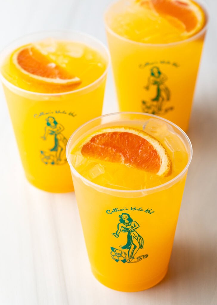 3 sunny d vodka seltzer drinks, each in a glass cup with slice of orange on top.