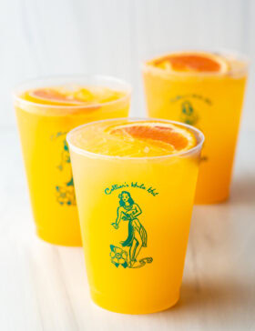 3 sunny d vodka seltzer drinks, each in a glass cup with slice of orange on top.