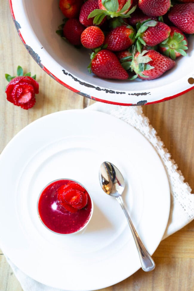 Top down view small glass dish with silky swedish kreme topped with berry compote and strawberry rose.