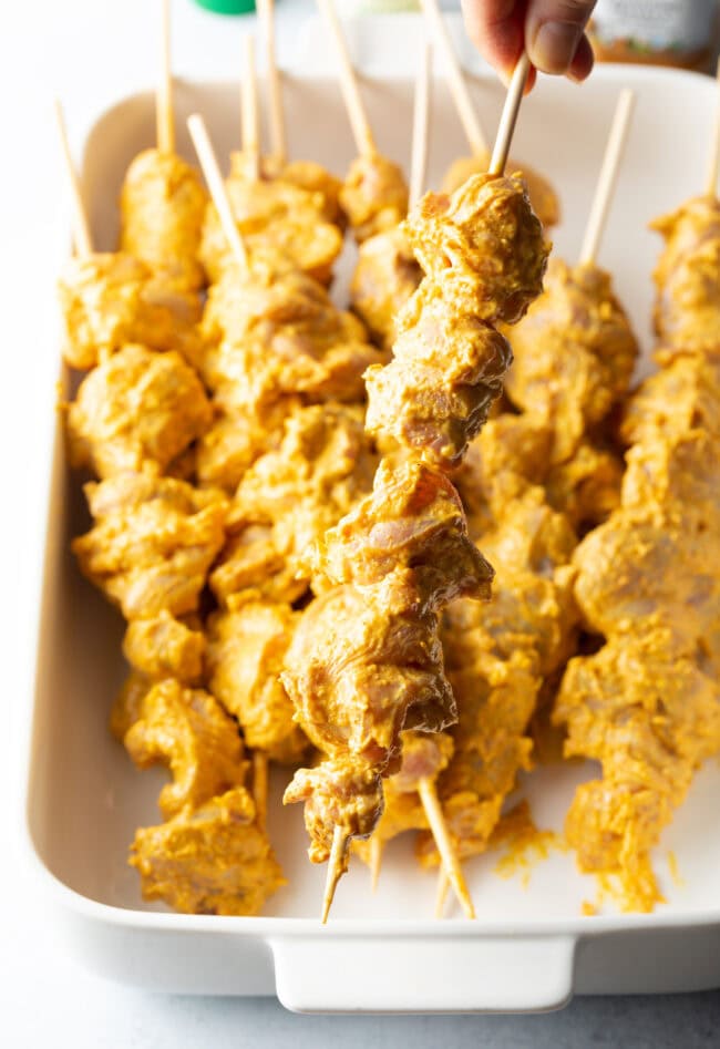 Chunks of chicken on wood, each piece coated in a blend of yogurt and spices.