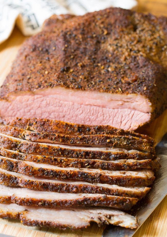 Brisket on a cutting board with slices off the side. 