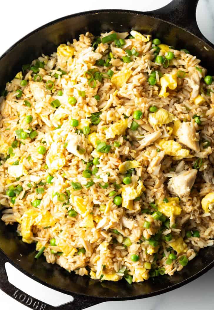 Black cast iron skillet with crab fried rice with chunks of crab meat and peas.