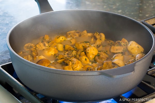 Mushrooms with seasonings sautéing in a pan on the stove. 