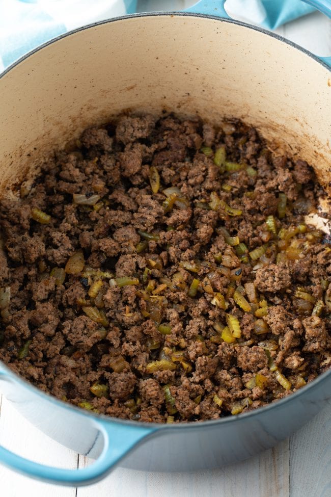 Ground beef and celery being cooked in a large pot. 