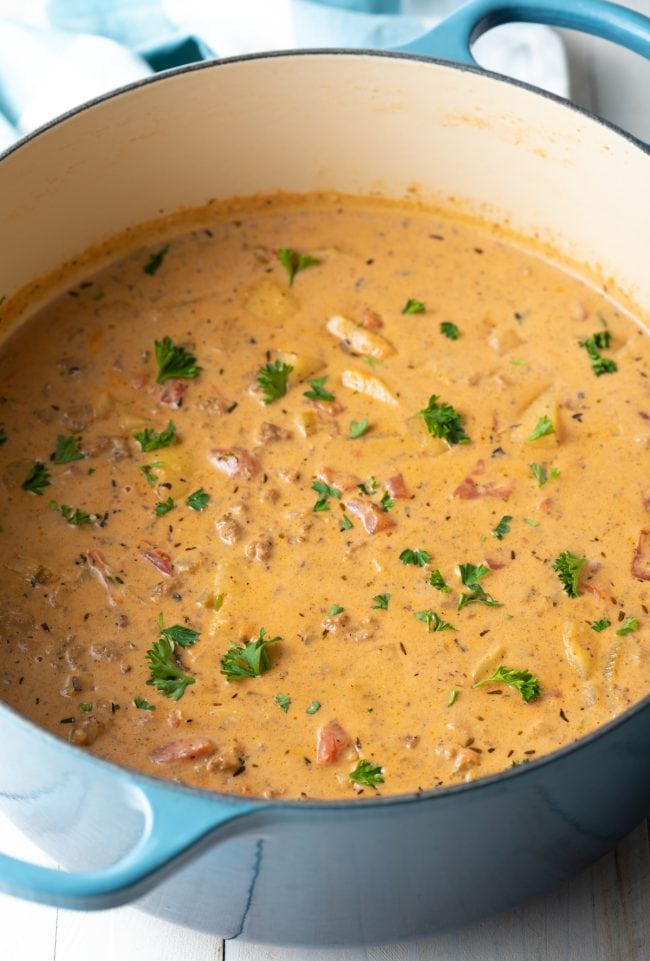 Bacon Cheeseburger Soup in a dutch oven and garnished with parsley. 