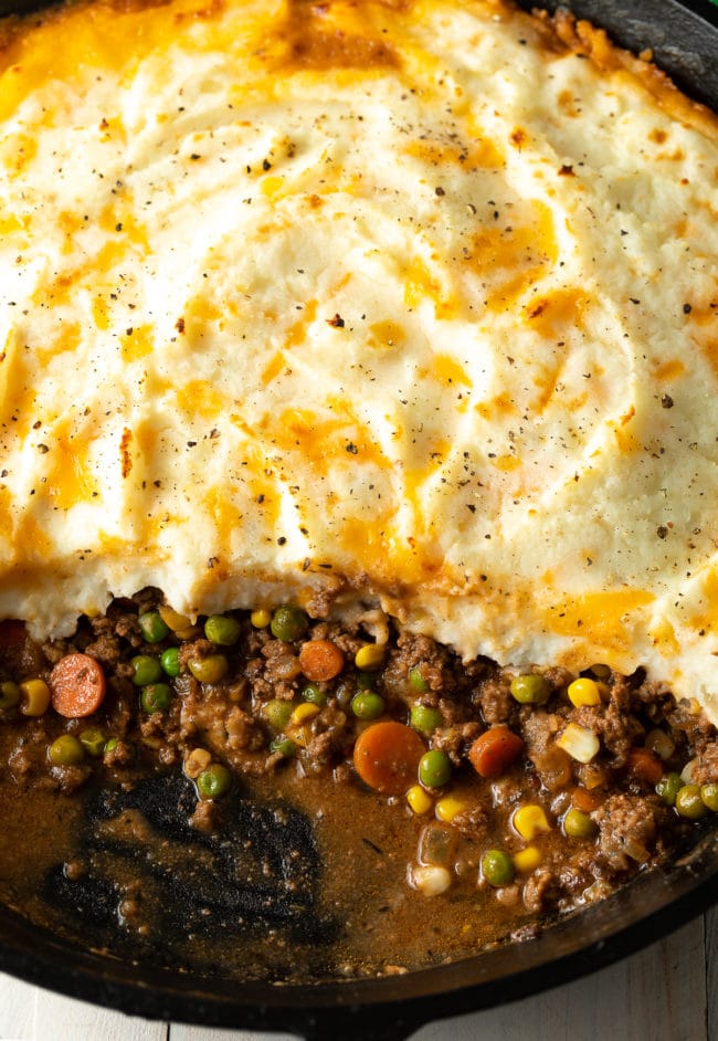 Cottage pie with beef with some of it missing to see the inside filling. 