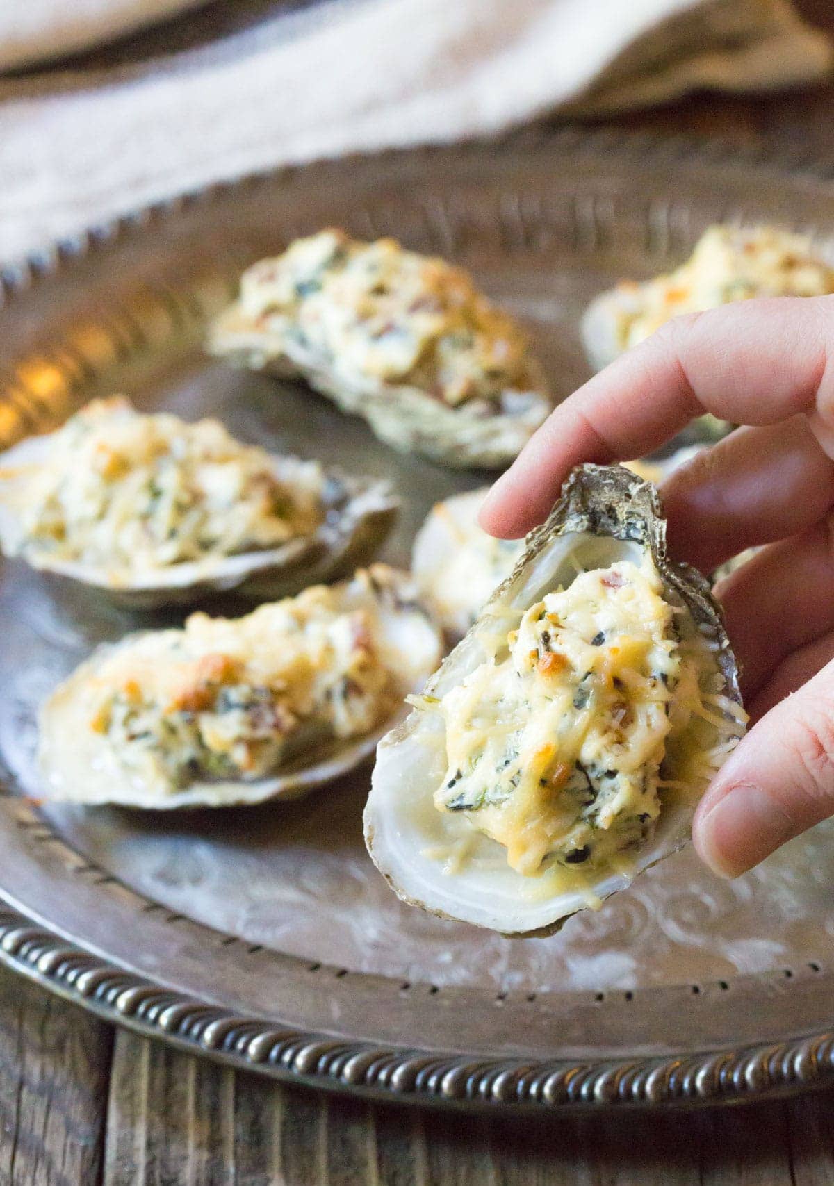 Baked Oysters Recipe - Close up of cheese filled oyster in hand