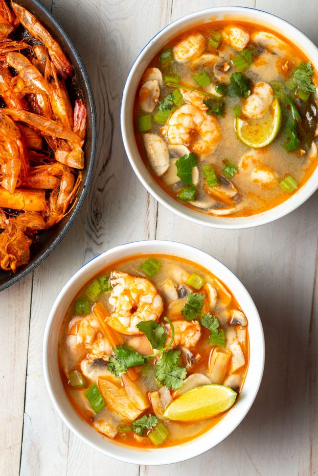 Overhead shot of two bowls of shrimp tom yum soup. 