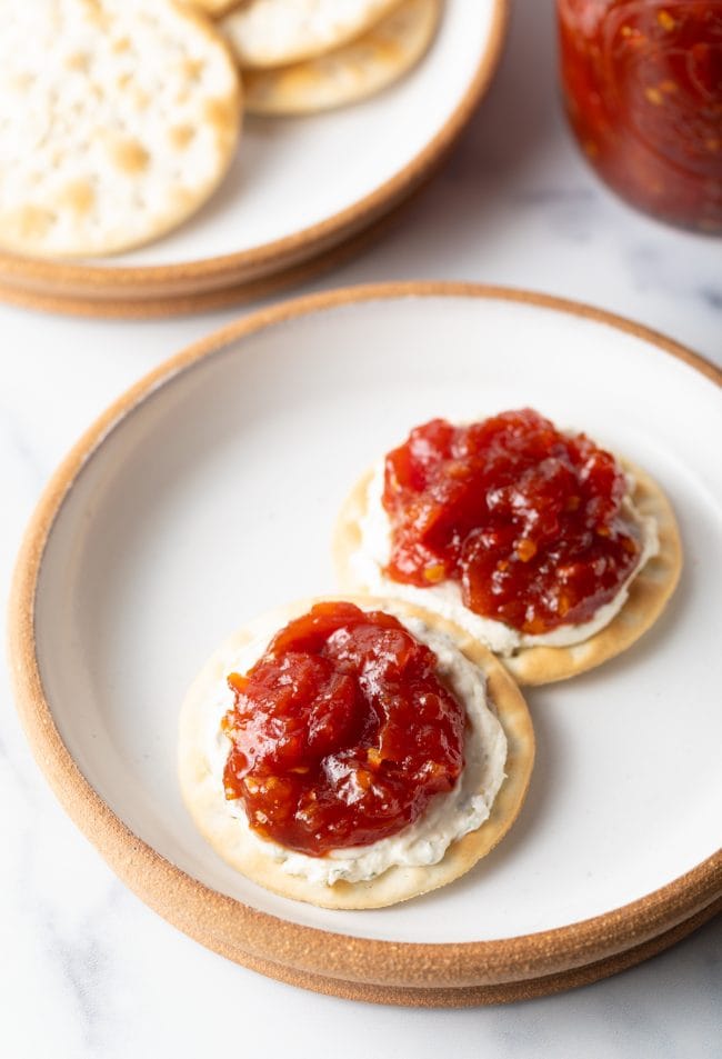 Overhead view of plate with two crackers, with cheese and dollop of this tomato jam recipe.