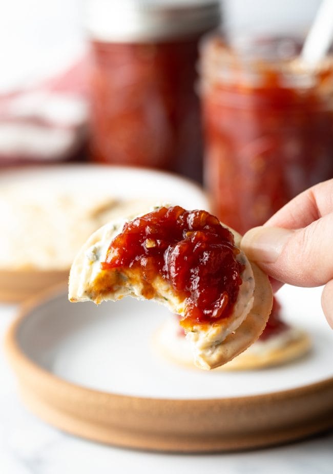 Bite of cracker with cheese and homemade jam made with tomatoes.