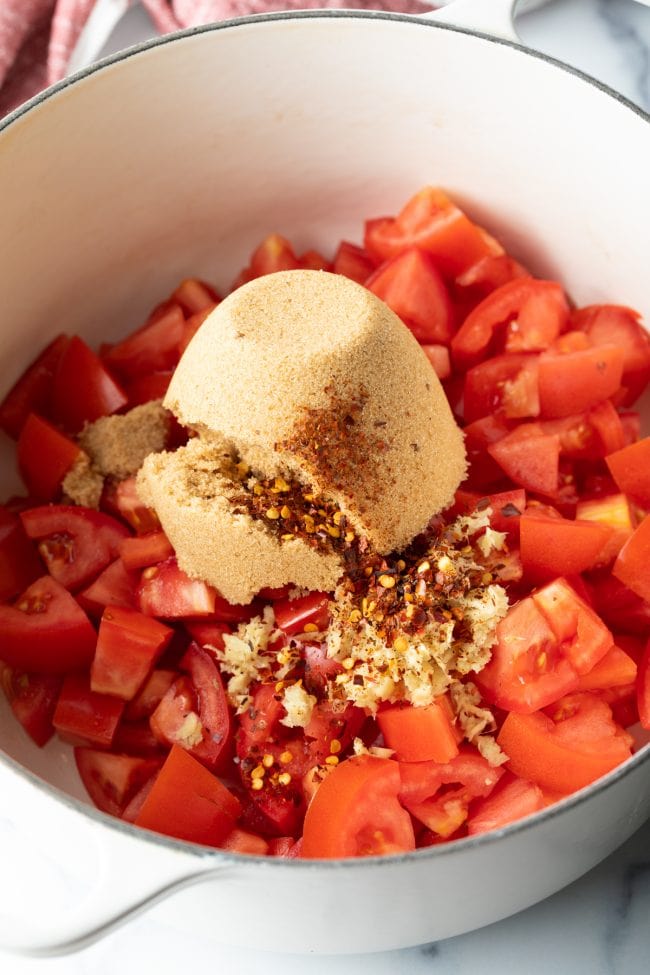 Adding brown sugar and seasonings to the pot with the tomatoes. 