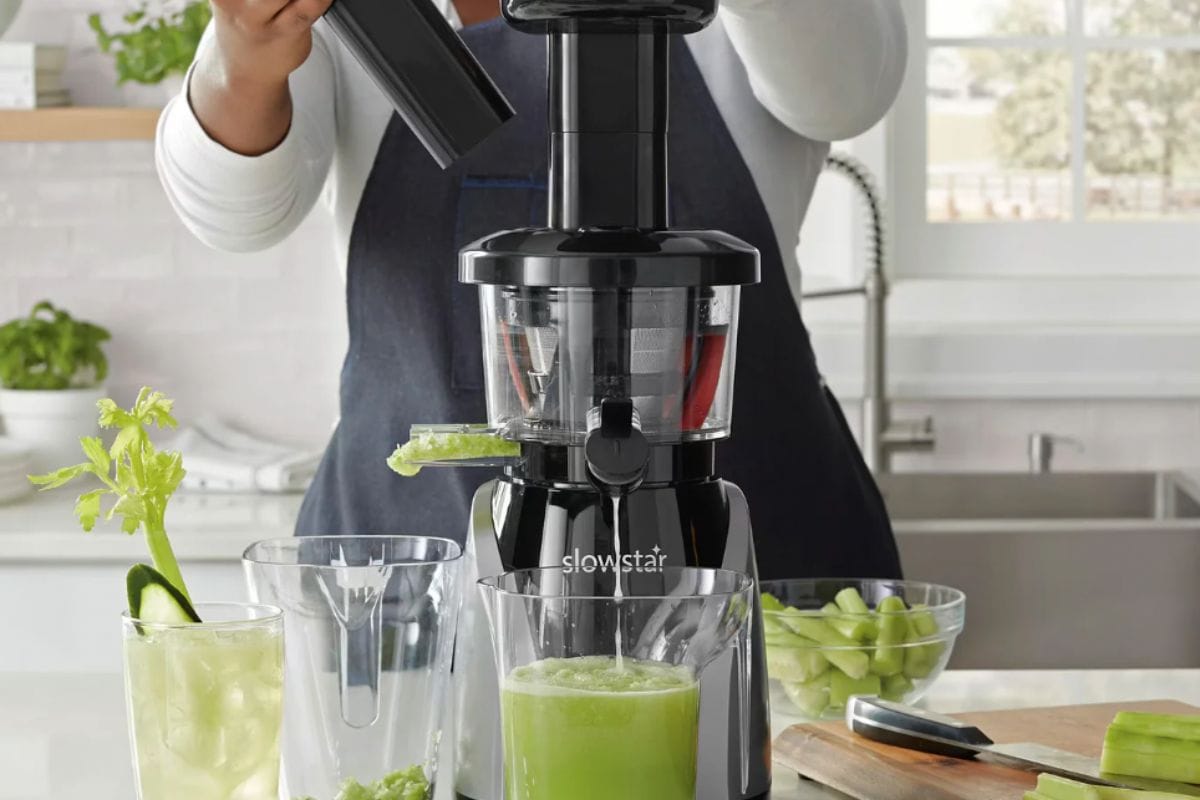 Person standing behind juicer while juicing celery. 