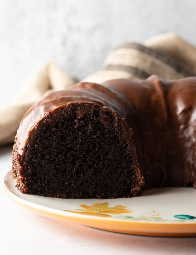 Triple chocolate Bundt cake with thick chocolate glaze. Segments of the cake have been removed to show the inside crumb of the cake.