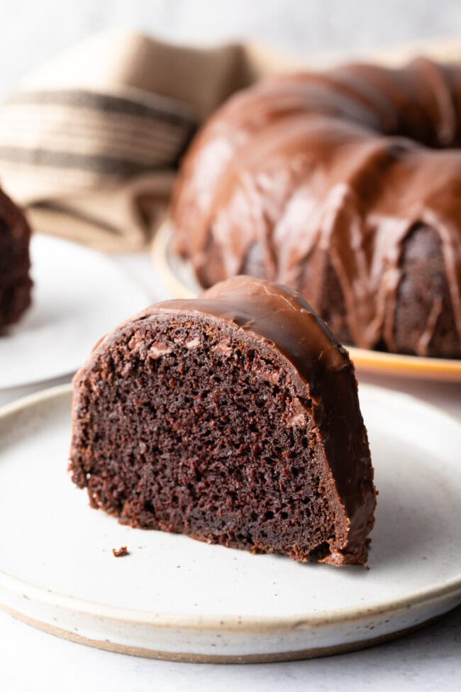 Slice of chocolate glazed cake on a white plate.