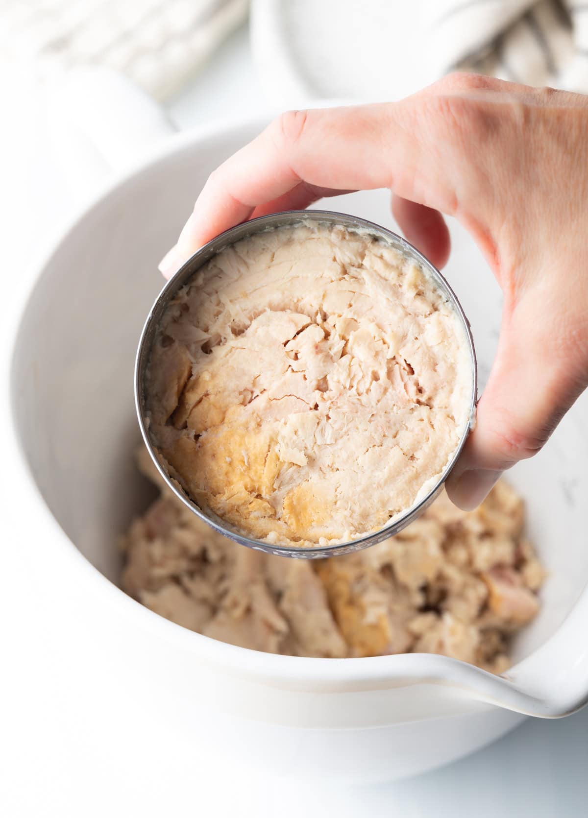 a hand holding canned tunafish in water