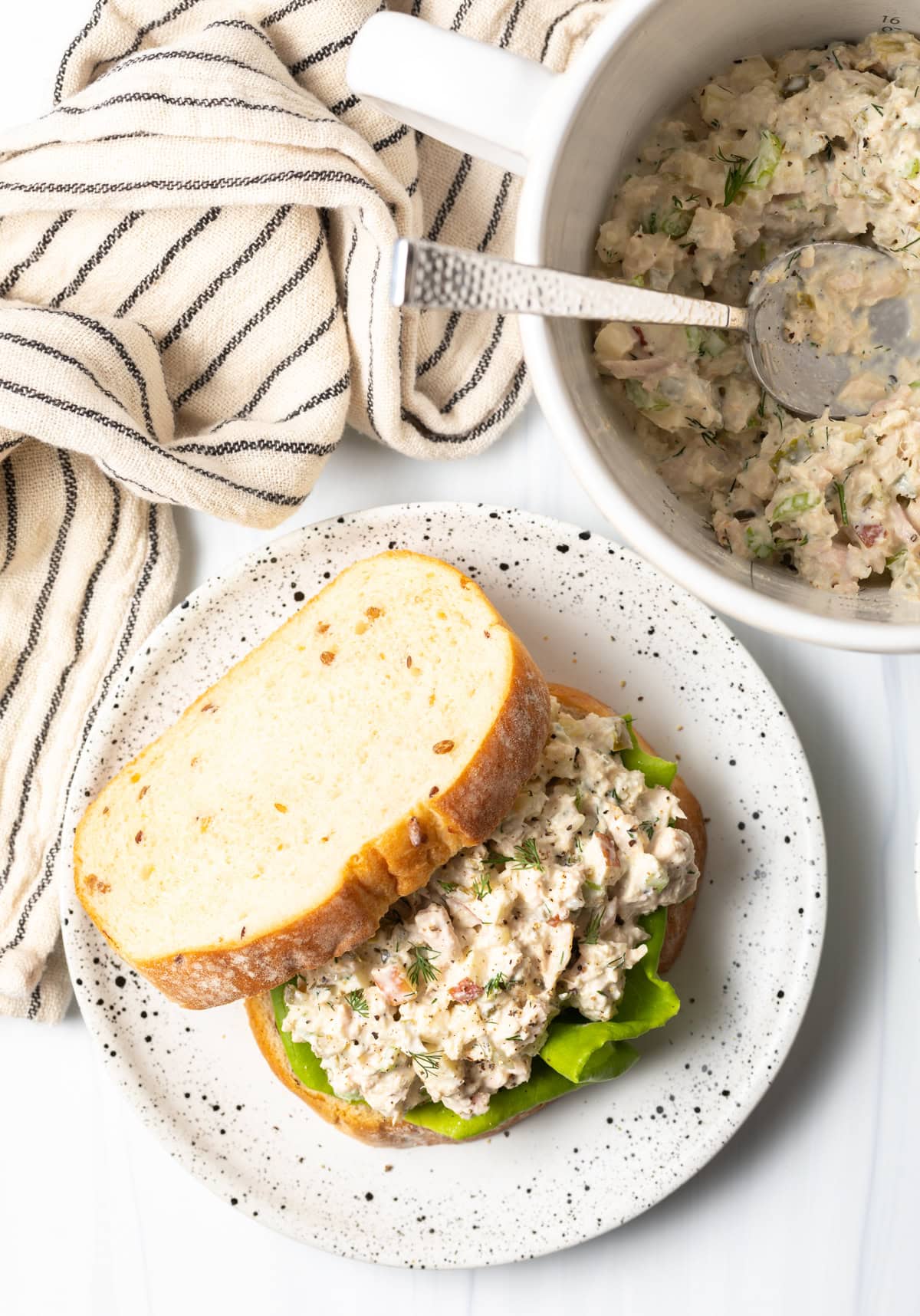 classic tuna salad sandwich on a white speckled plate.