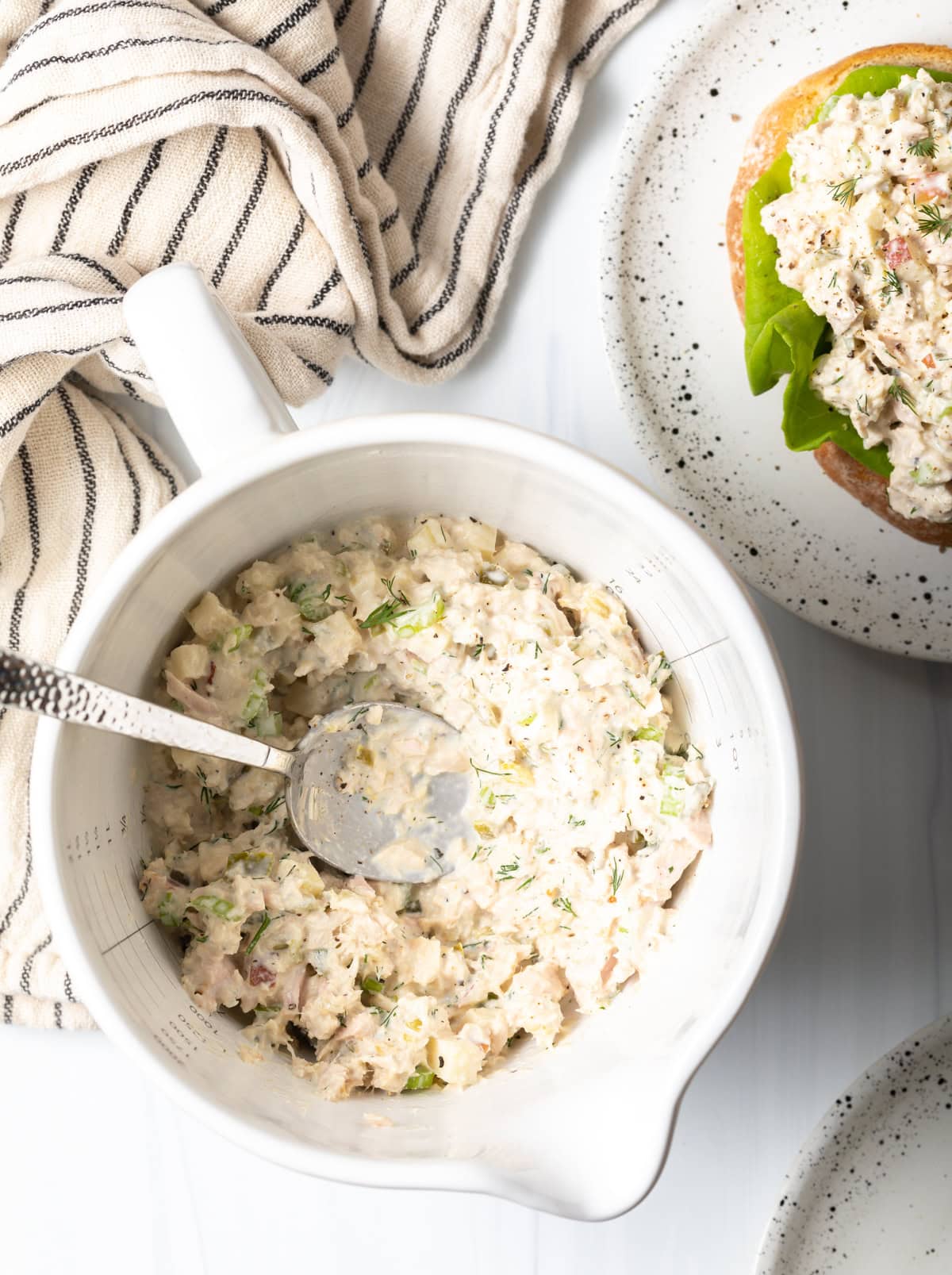 a white bowl of unique tuna salad overhead with a spoon.