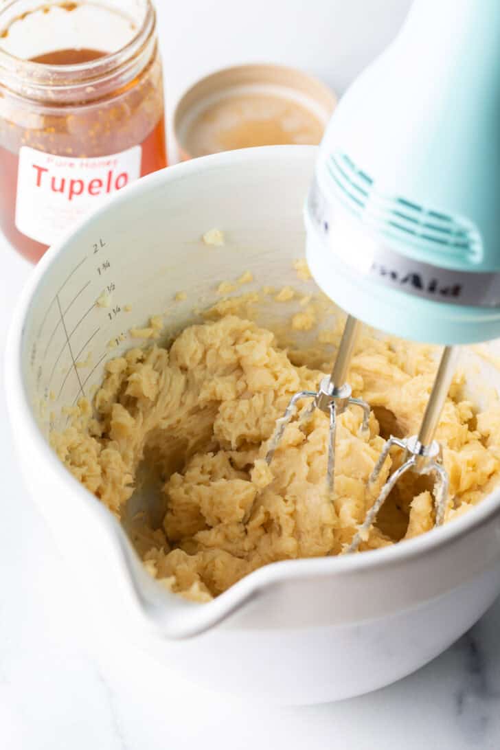 Using an electric hand mixer to blend butter, honey, and seasonings.